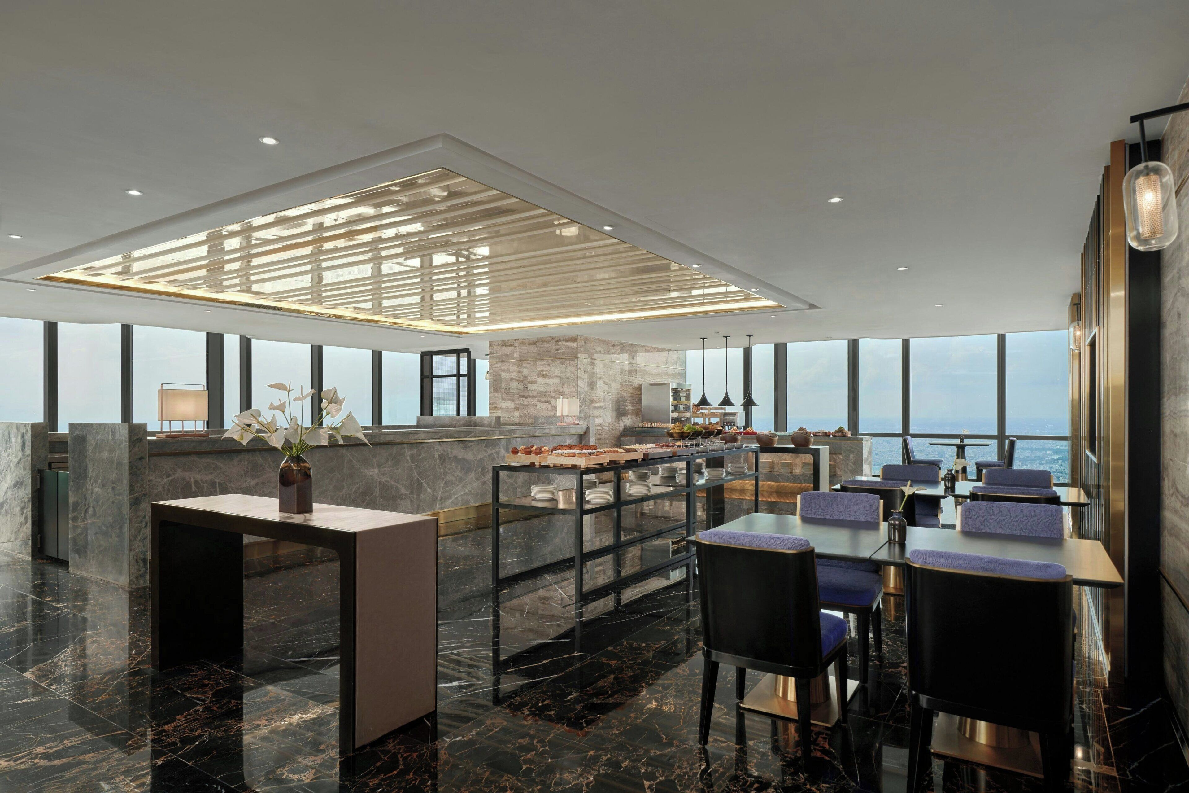 Un comedor moderno con techo alto, suelo de mármol y vistas a la ciudad.