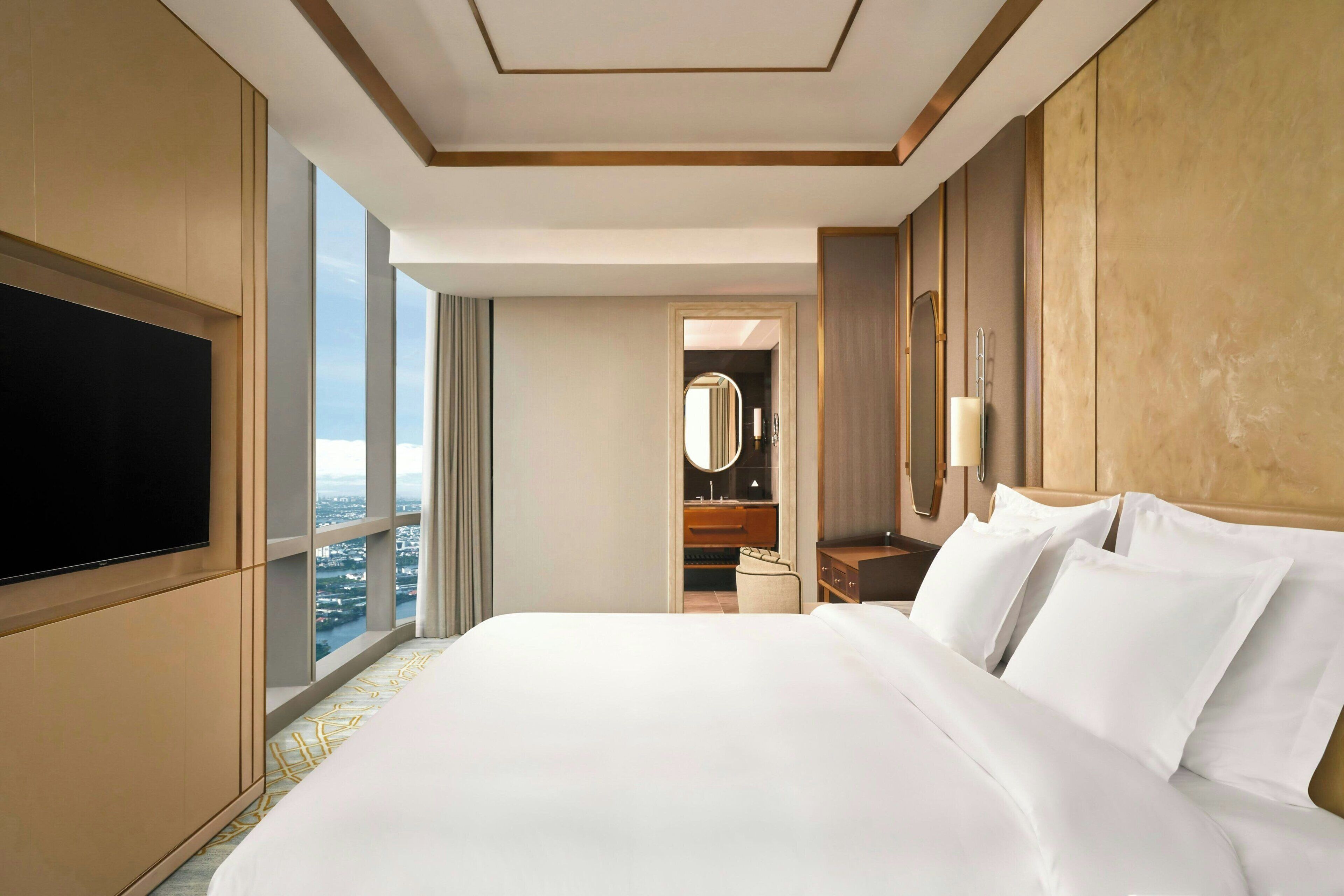 Une chambre d’hôtel avec un grand lit, une télévision à écran plat, une salle de bain avec un miroir et une vue sur la ville.