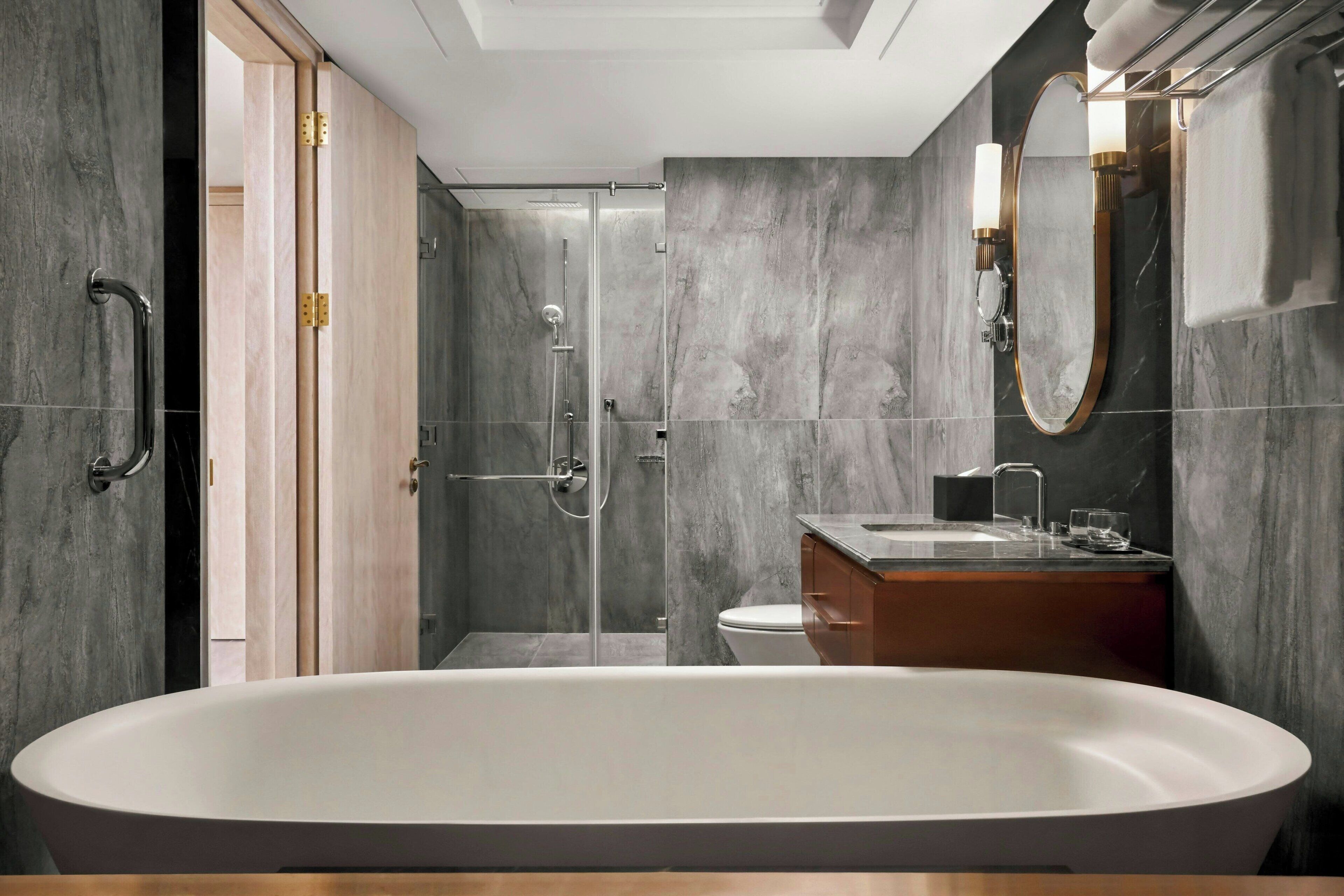 A modern bathroom with a freestanding bathtub, a glass-enclosed shower, and a wooden vanity.