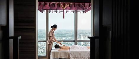 A massage therapy room with a large window overlooking a cityscape.