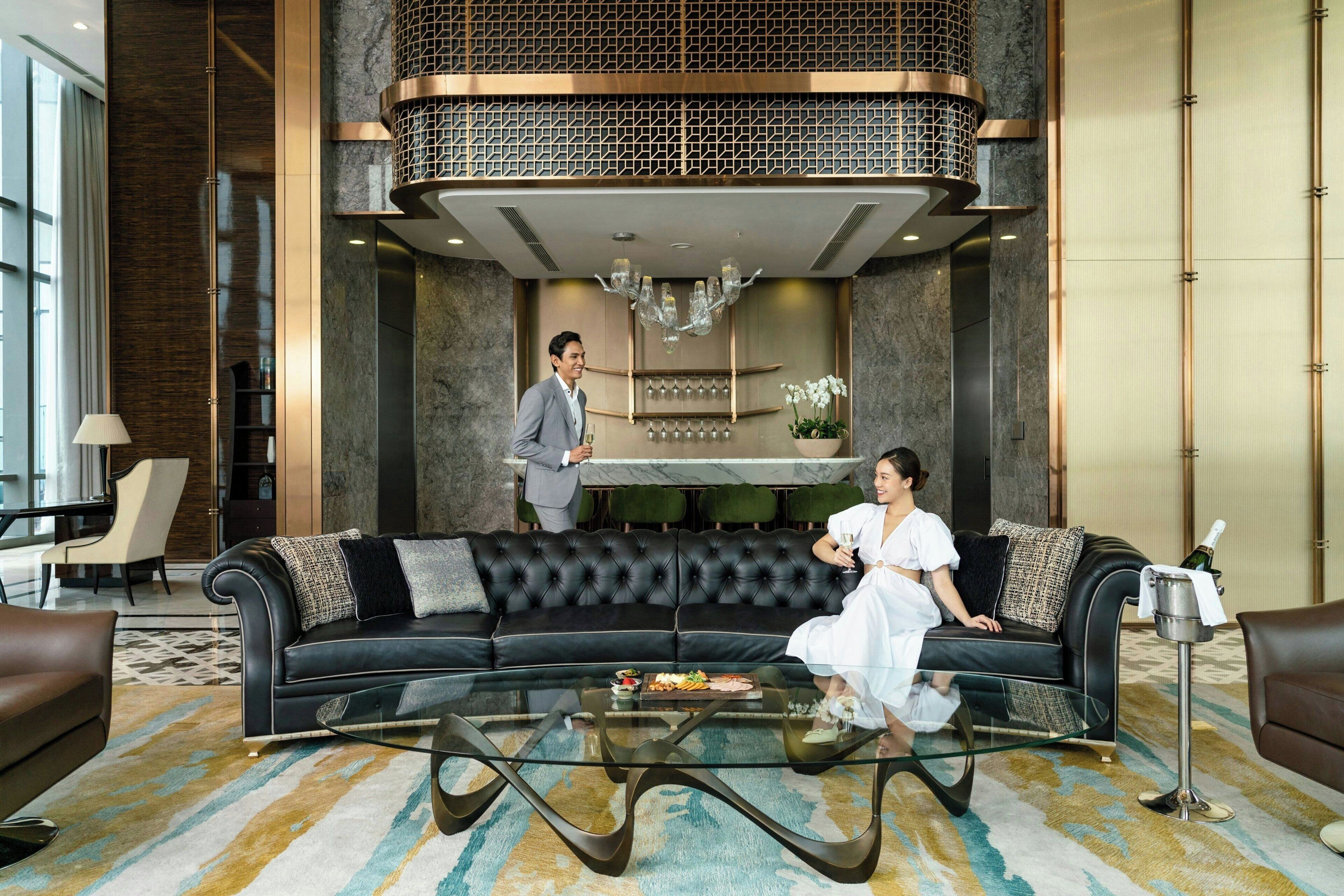 Un'elegante hall moderna con un divano in pelle nera, un tavolino in vetro e un lampadario.