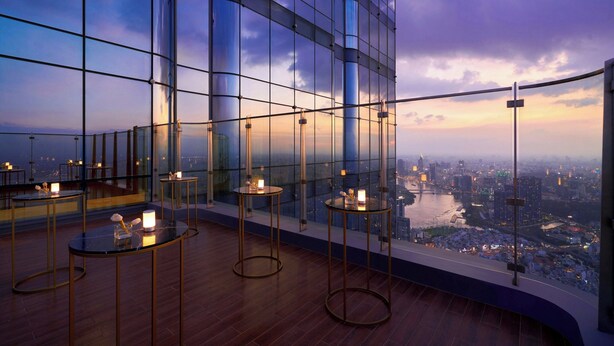 Interior de un edificio alto con ventanas amplias que ofrecen vistas a la ciudad, incluyendo un río y el horizonte.