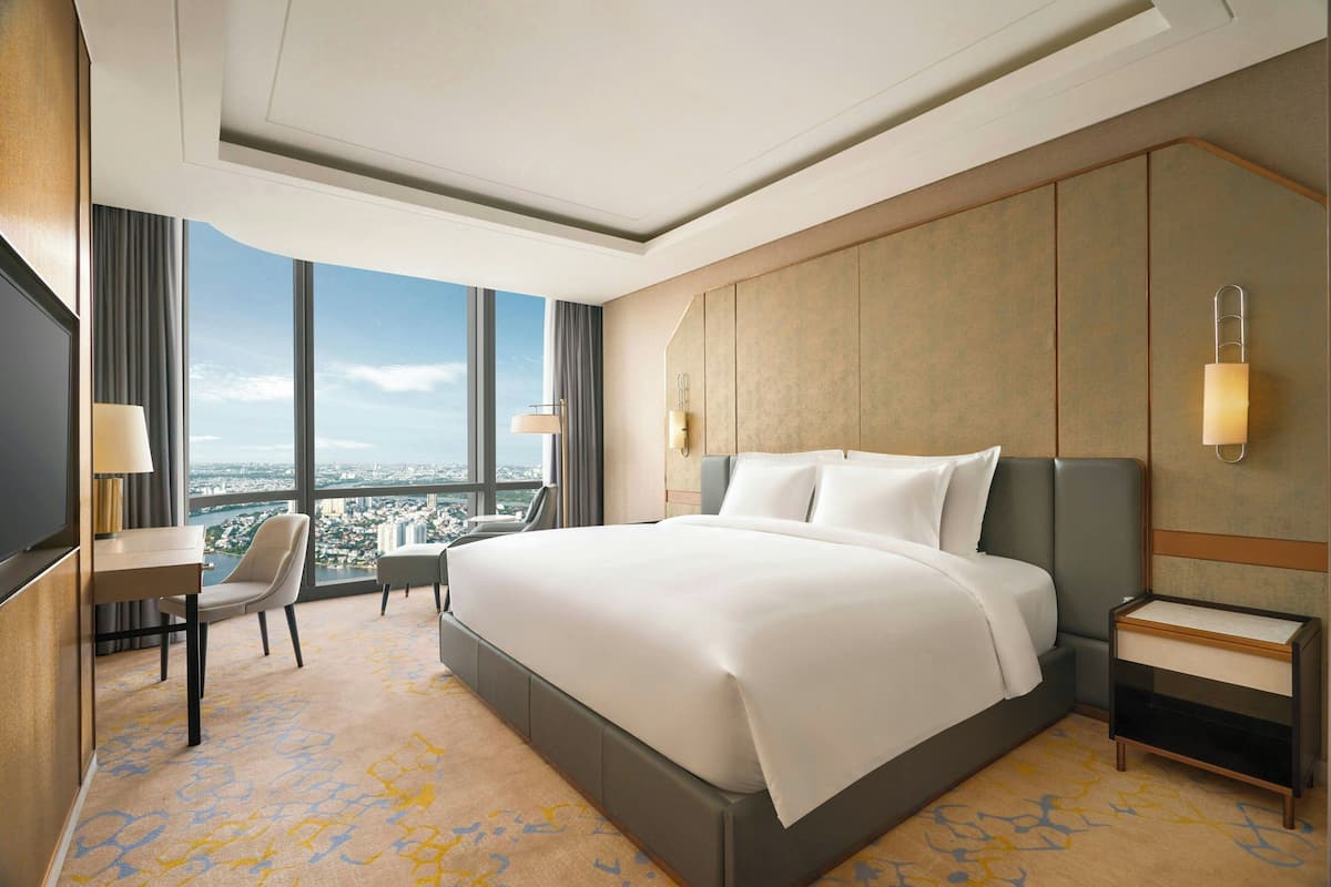 Habitación de hotel con una cama grande, un escritorio, una silla y vistas a la ciudad.