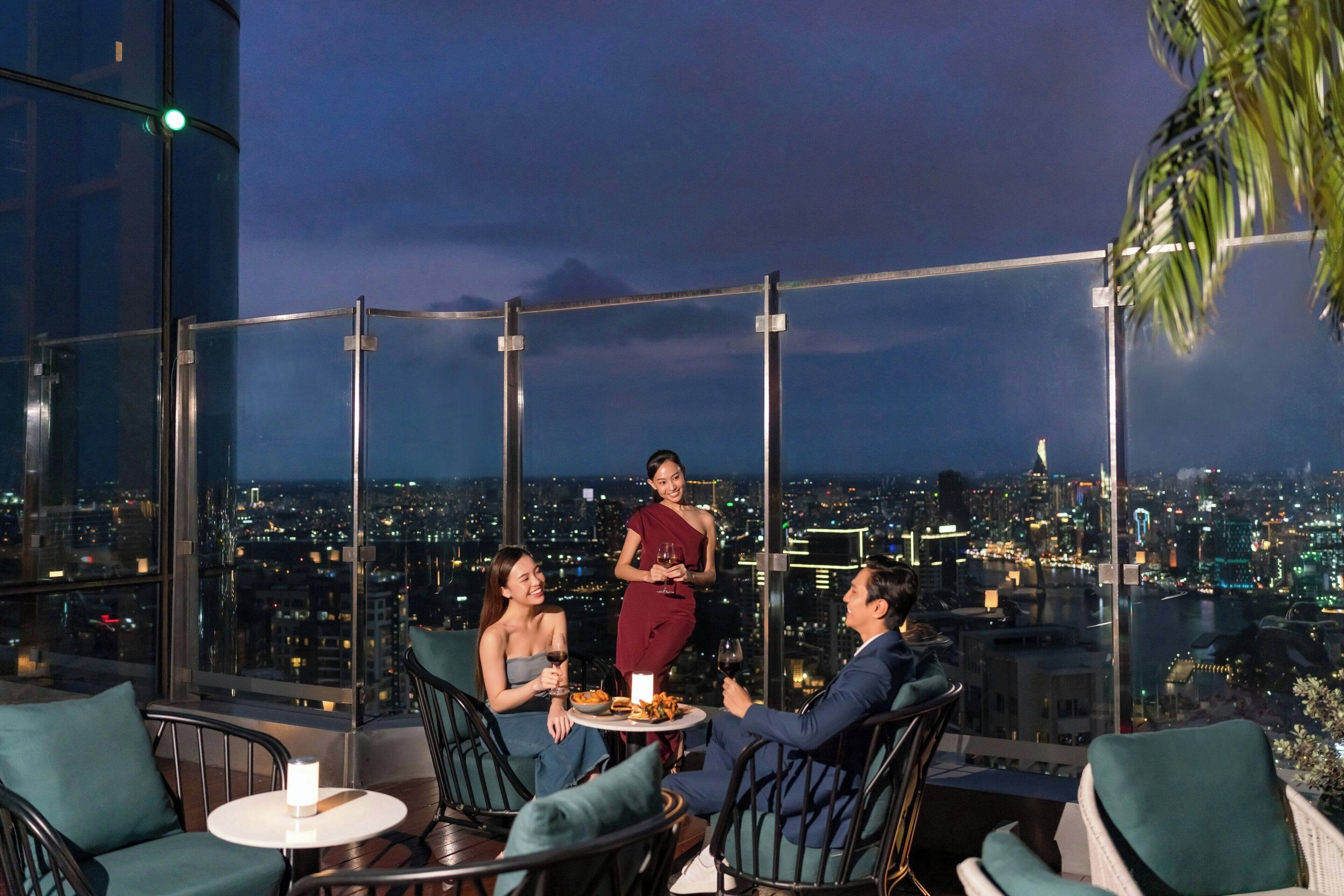 Un restaurante de altura con vistas panorámicas de la ciudad, muebles modernos y un área de comedor con paredes de vidrio.
