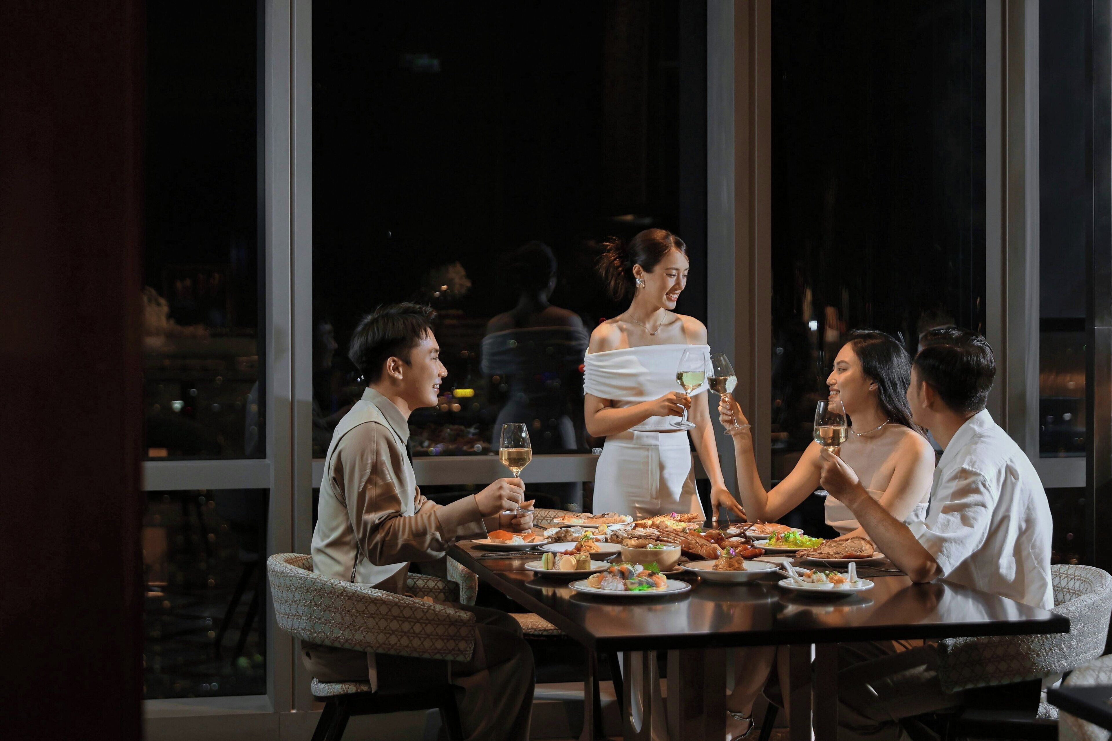 Un grupo de personas cenando en una mesa con vistas a la ciudad de noche.