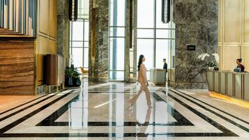 A spacious lobby with a polished marble floor, large windows, and a reception desk.