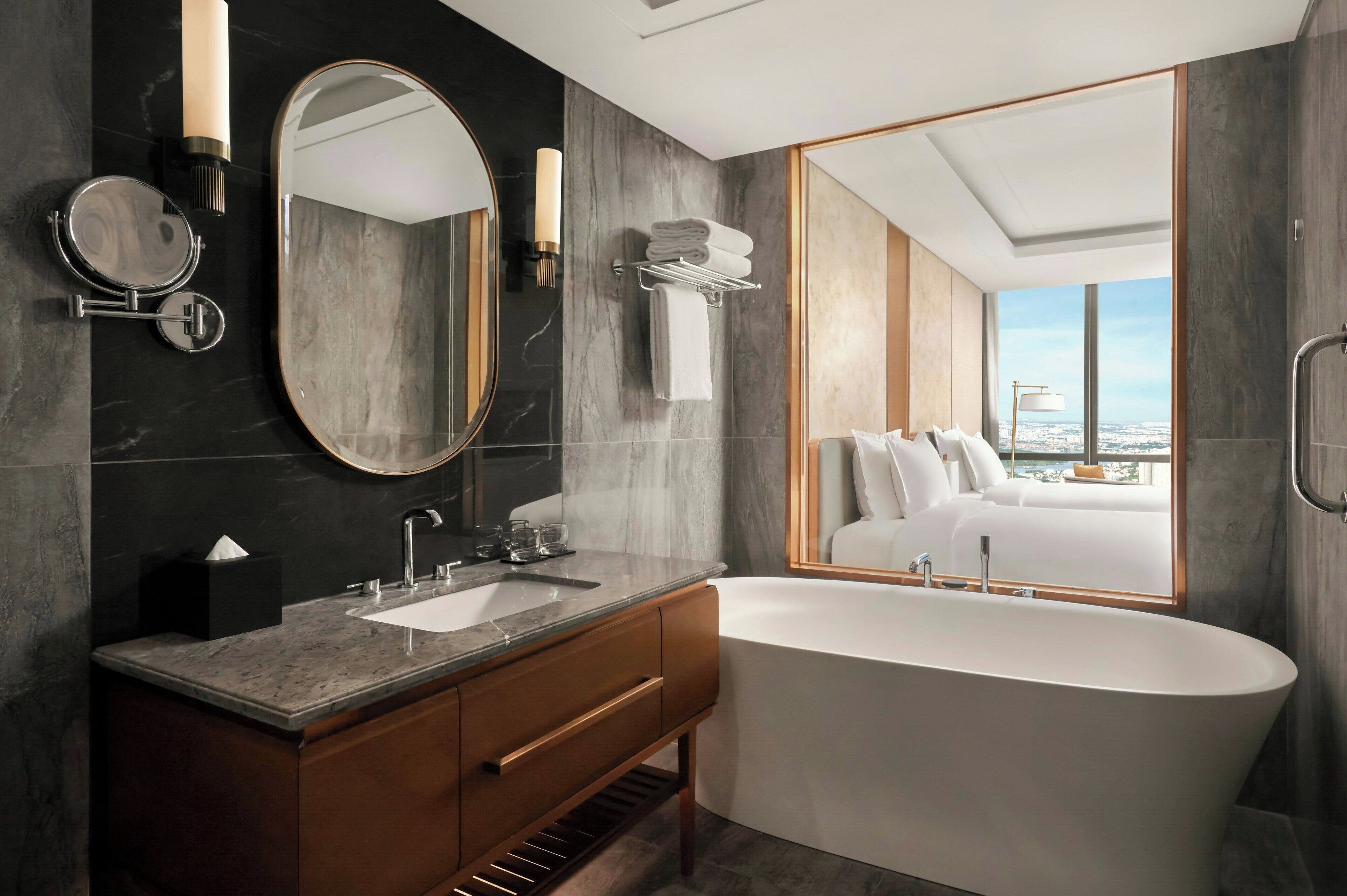 Une salle de bain moderne avec une baignoire sur pieds, un grand miroir et un meuble-lavabo doté d’un évier et d’un porte-serviettes.