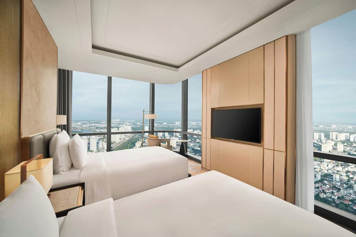 Una habitación de hotel moderna con dos camas, televisión y vistas a la ciudad.