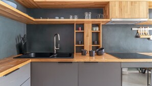Een moderne keuken met een houten aanrecht, een zwarte spoelbak en inbouwkeukenmeubels.