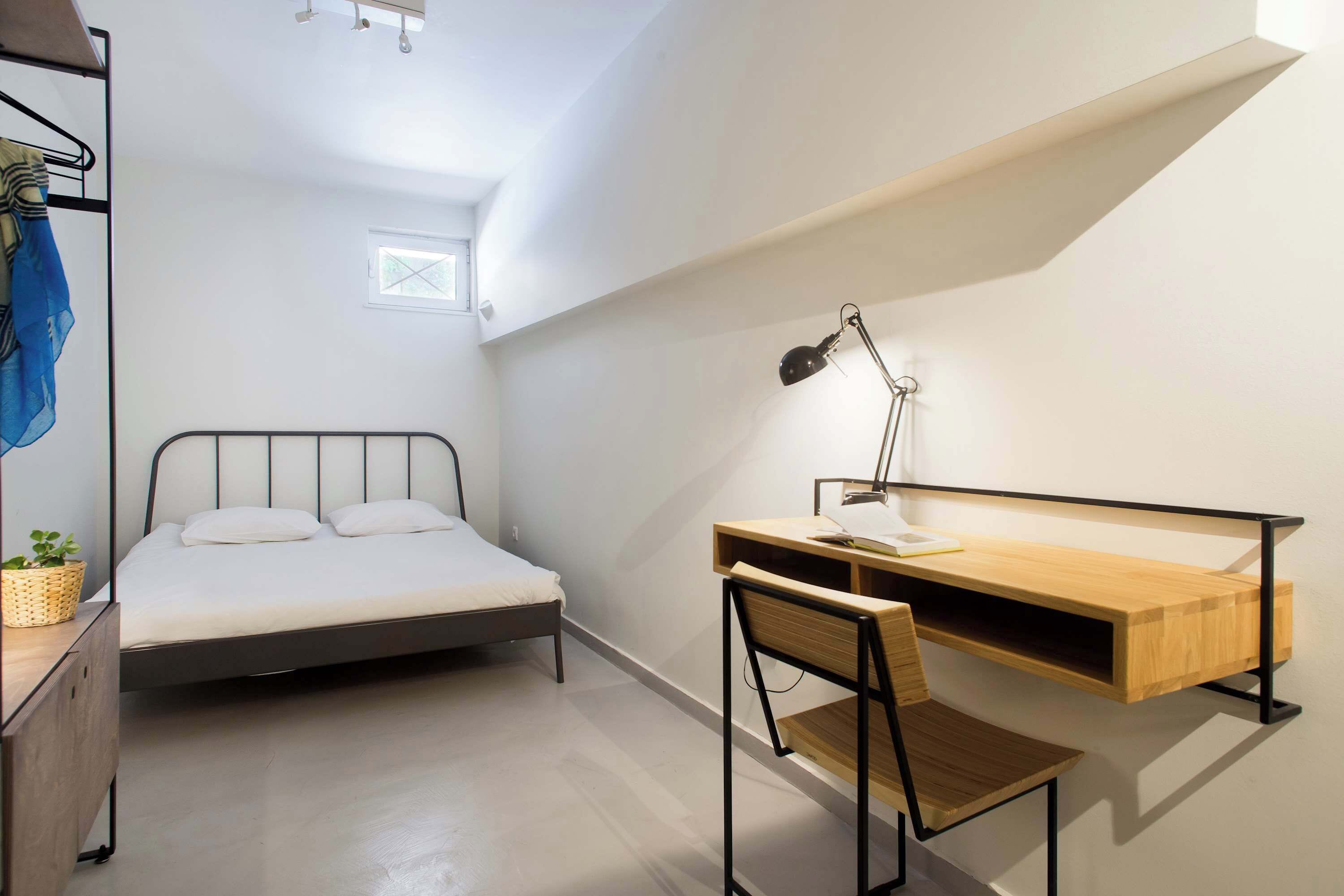 Une chambre à coucher de taille réduite, comprenant un lit, un bureau et une chaise.