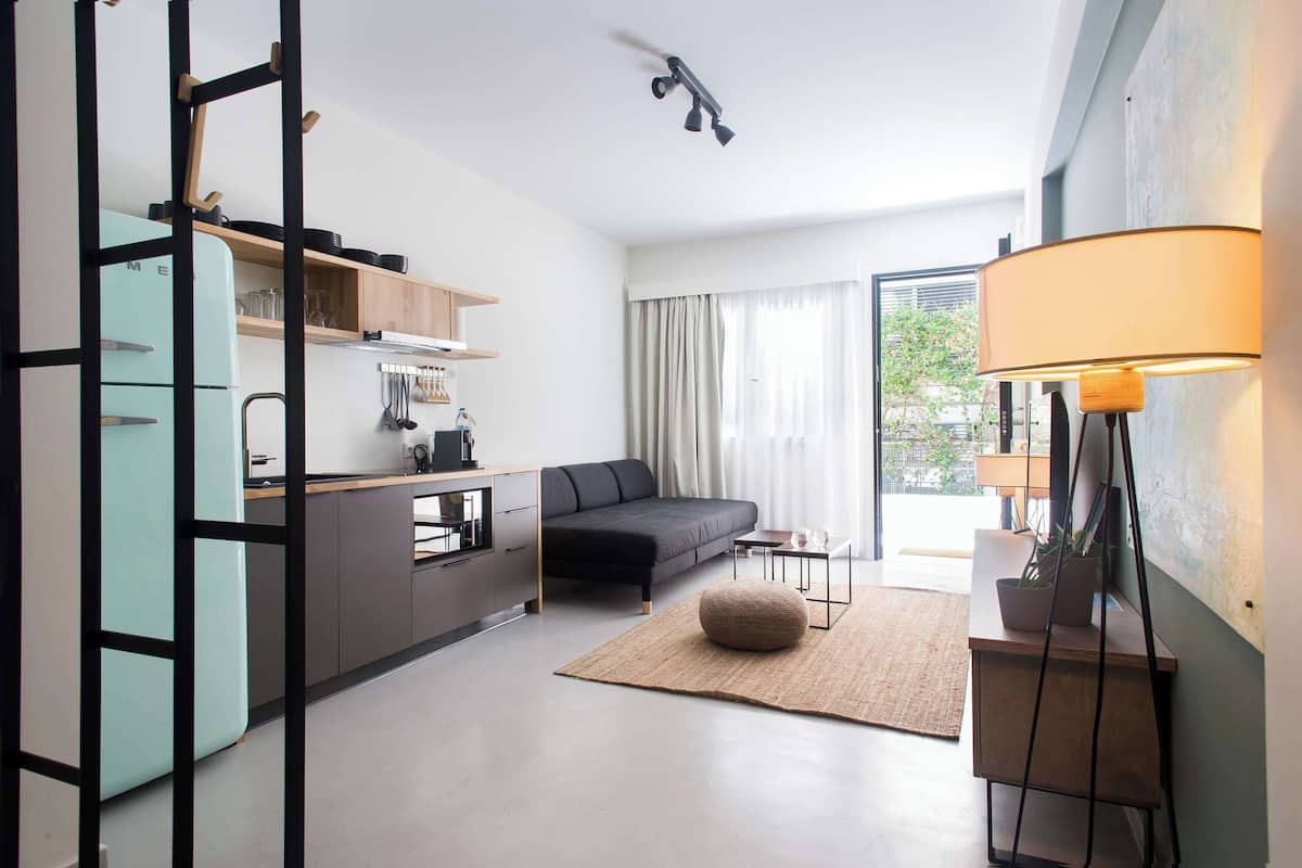 A modern living space with a kitchen, a sofa, a dining table, and a lamp.
