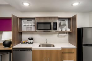 Una cocina moderna con microondas integrado, cafetera y pileta de acero inoxidable.