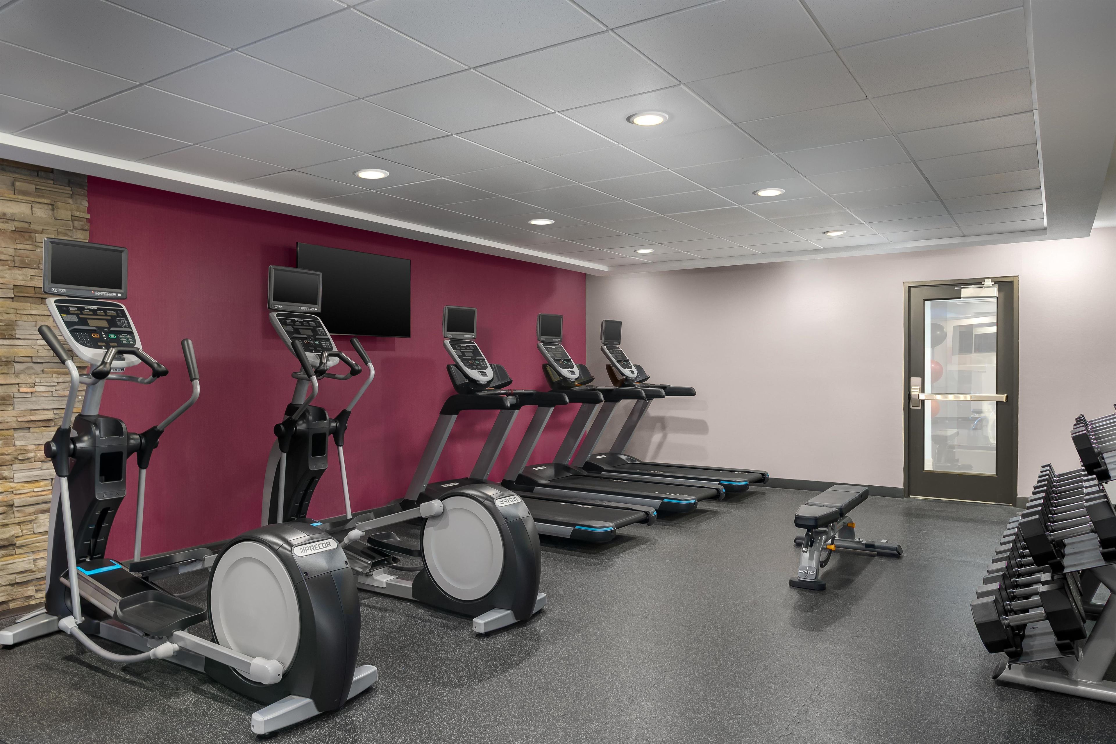 A gym with treadmills, ellipticals, and dumbbells.