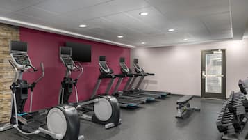 A gym with treadmills, ellipticals, and dumbbells.