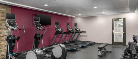 A gym with treadmills, ellipticals, and dumbbells.