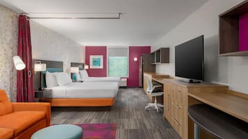 A hotel room with a bed, a desk, a television, and a seating area.