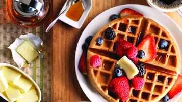 Waffles served with fresh berries, butter, and a hot beverage.