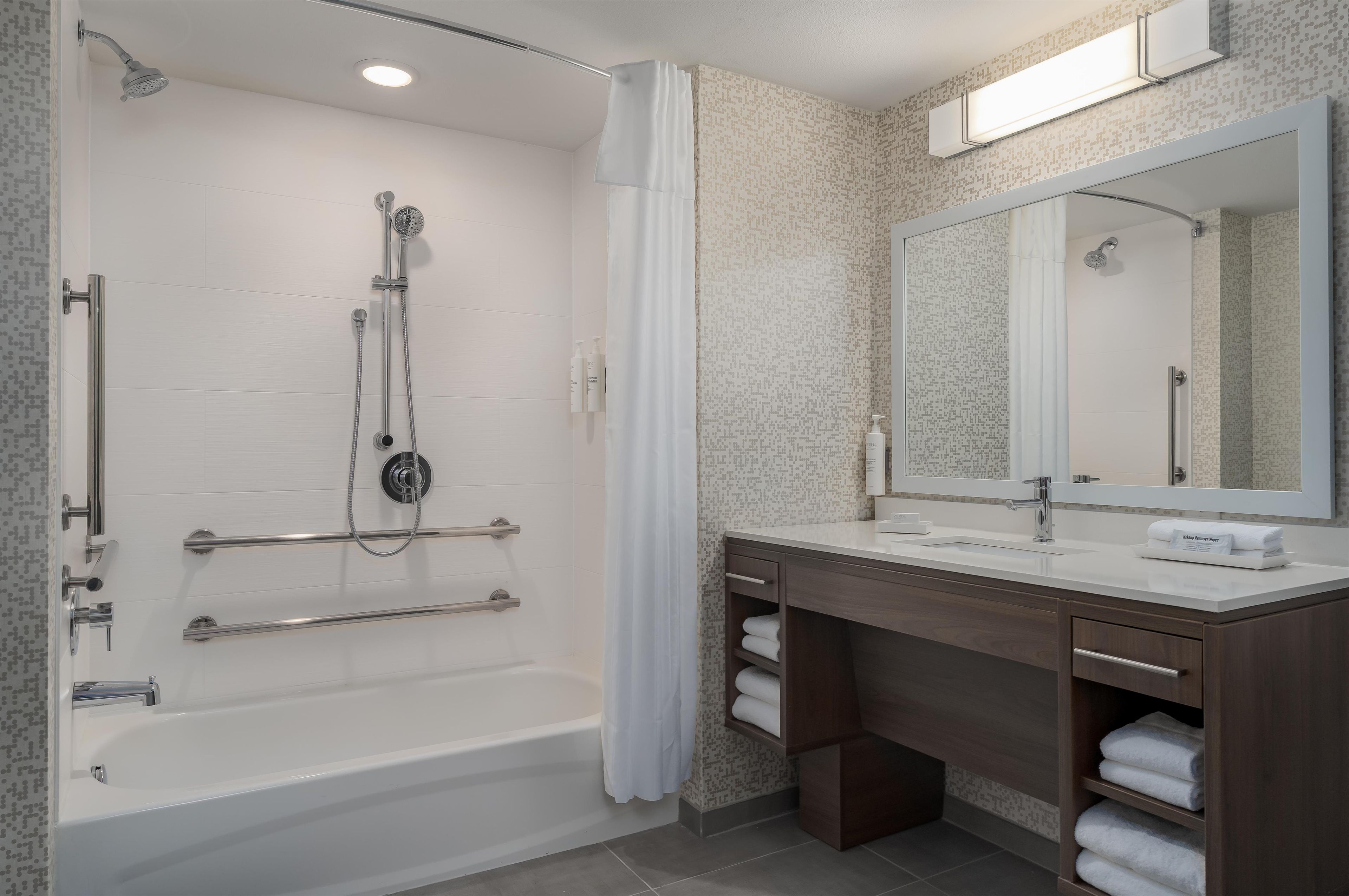Un baño moderno con bañera, ducha, tocador y un espejo grande.