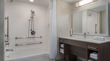 Un baño moderno con bañera, ducha, tocador y un espejo grande.