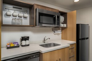 A modern kitchen with a built-in dishwasher, a coffee maker, a microwave, and a refrigerator. - Home2 Suites by Hilton Portland Hillsboro (Hillsboro)