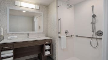 Ein modernes Badezimmer mit Dusche, Waschbecken und Spiegel sowie einem Handtuchhalter.