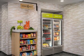 Mostrador de aperitivos con papas fritas y otros bocadillos, una sección refrigerada con bebidas, y un cartel que indica zonas 'frío' y 'muy frío'.