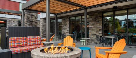 An outdoor seating area with a fire pit, wicker furniture, and stone walls.
