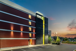 A modern hotel building with a prominent 'HOME 2' sign, multiple windows, and a parking lot. - Home2 Suites by Hilton Portland Hillsboro (Hillsboro)