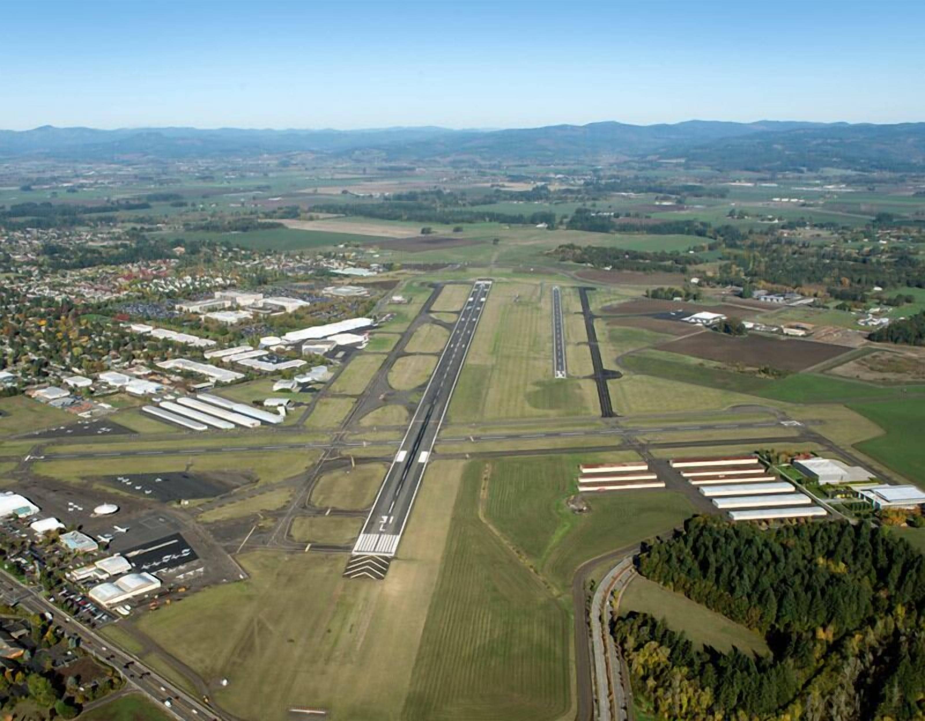 An airport runway with multiple taxiways and hangars.