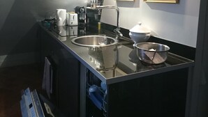 A modern kitchen with a stainless steel island, a built-in dishwasher, and a microwave. There are two framed pictures on the wall above the island.