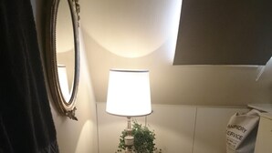 A small bathroom with a white sink, a mirror, a lamp, a towel, and a red rug.