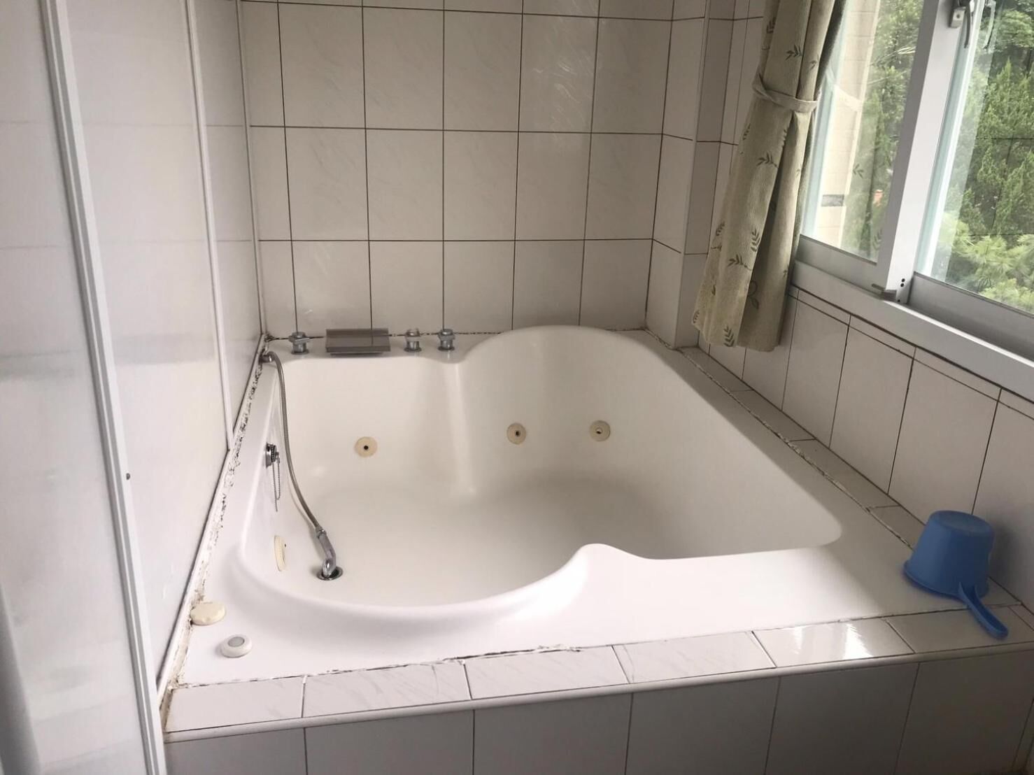Un baño moderno con una bañera independiente, una ventana con cortinas y una alfombra de baño azul.