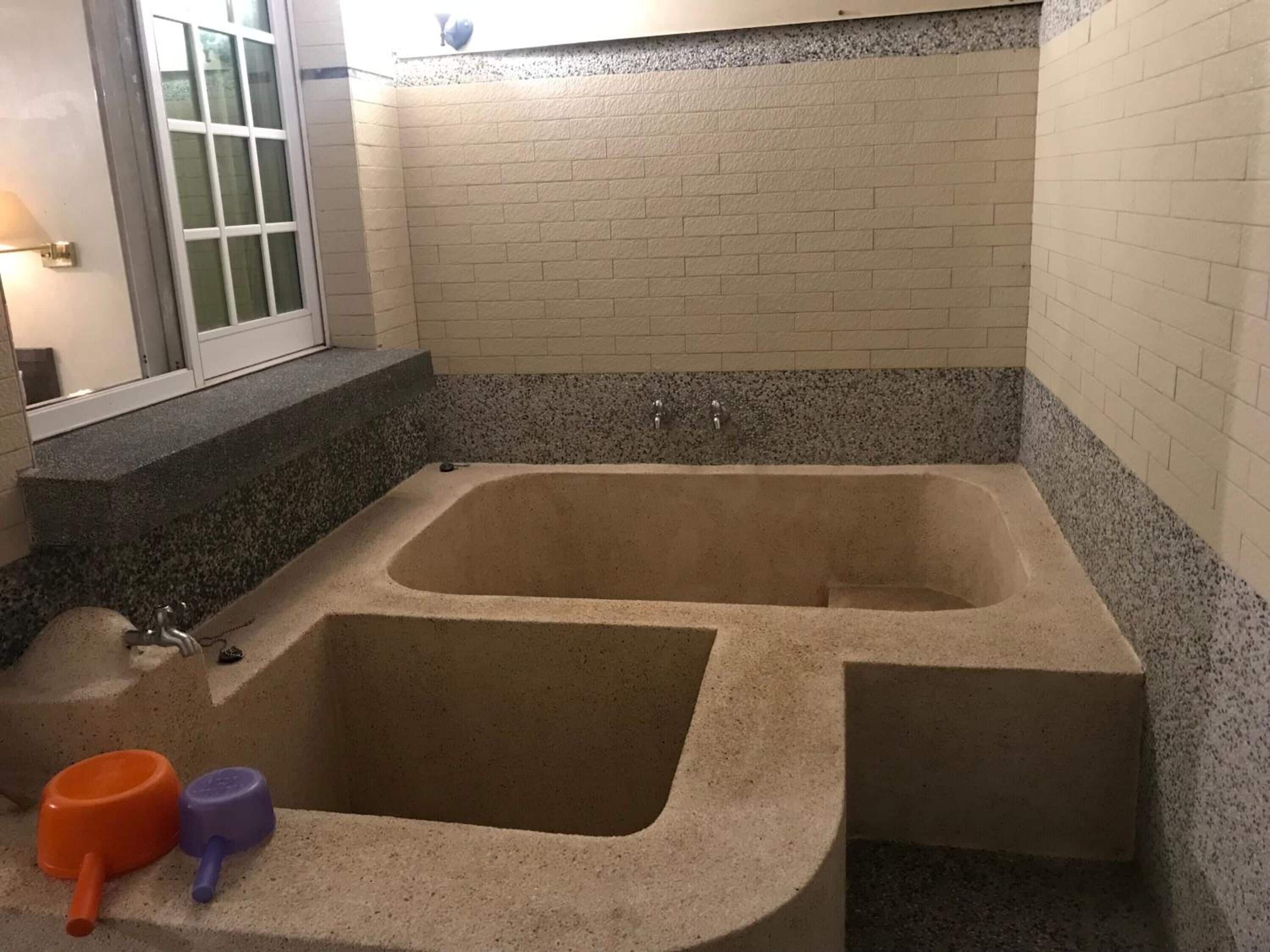 A bathroom with a large bathtub, a window, and a granite countertop.