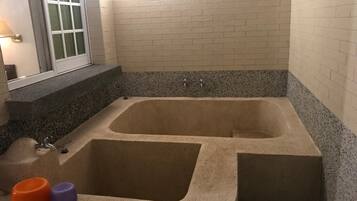 A bathroom with a large bathtub, a window, and a granite countertop.