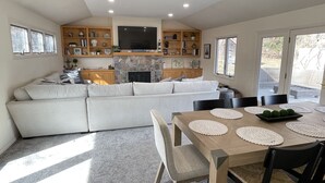 A modern kitchen with a stone fireplace, wooden cabinets, and a large TV. - Summer Sand & Fun Beachfront Vacation Traverse City In Cottage (Traverse City)