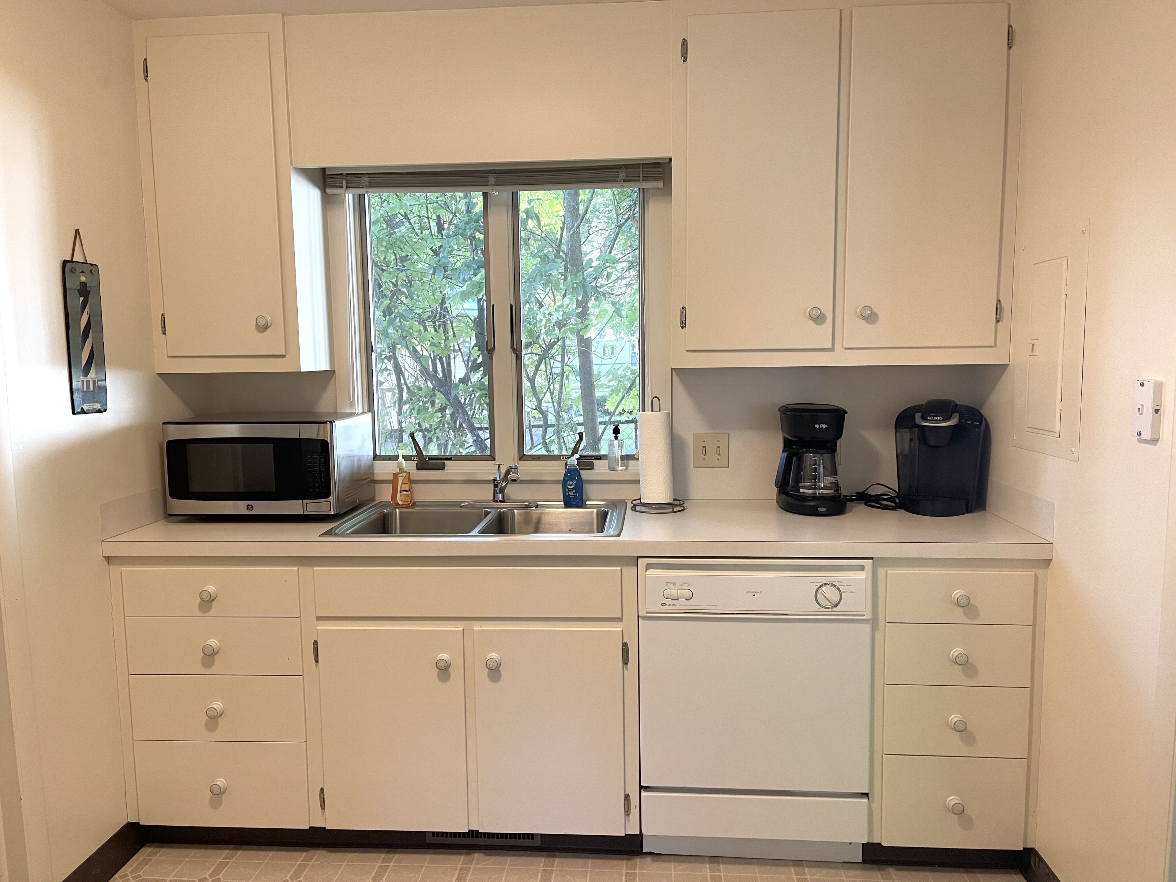 A kitchen with white cabinets, a microwave, a coffee maker, and a dishwasher.