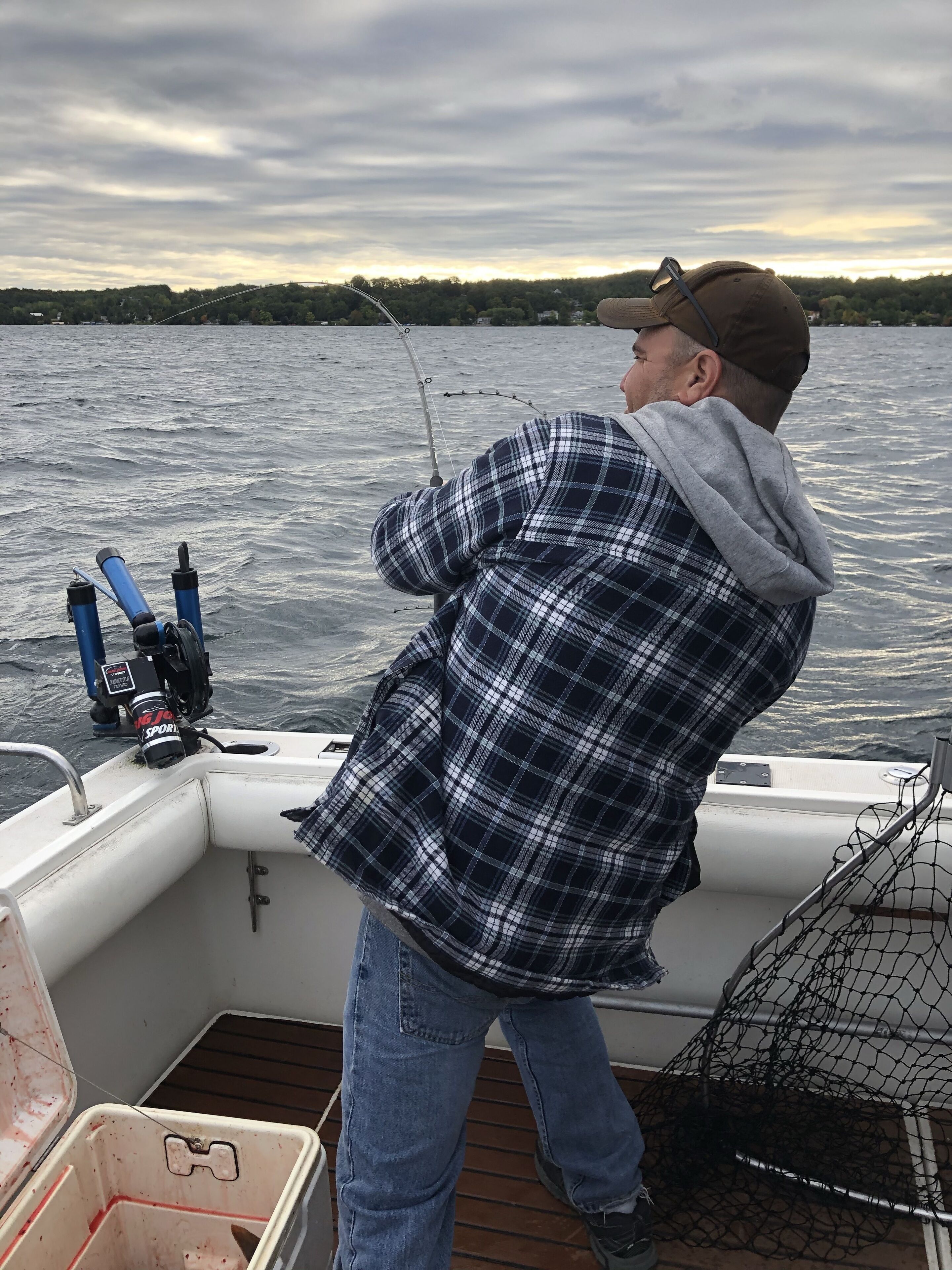 A person fishing on a boat with a net and fishing rods.