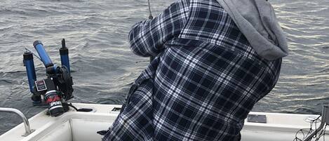 A person fishing on a boat with a net and fishing rods.