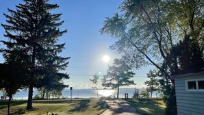 A paved driveway leading to a house with a view of the ocean and mountains in the distance. - Summer Sand & Fun Beachfront Vacation Traverse City In Cottage (Traverse City)
