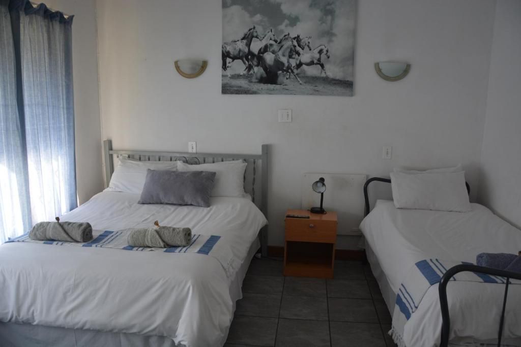 A hotel room with a large bed, a smaller bed, a nightstand with a lamp, and a painting on the wall.