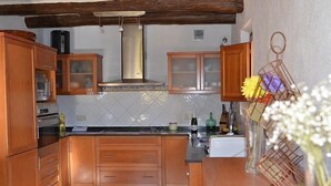 Une cuisine avec des meubles en bois, une cuisinière à gaz et un dosseret carrelé.