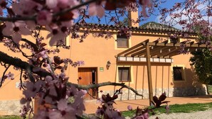 Un bâtiment dont la partie inférieure est en pierre et la partie supérieure en bois, avec une pergola en bois et un ciel dégagé.