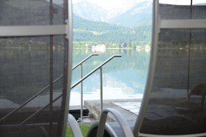 A view from a window with metal railings overlooking a calm lake and mountains. - Das Zimmerbräu (Sankt Wolfgang im Salzkammergut)