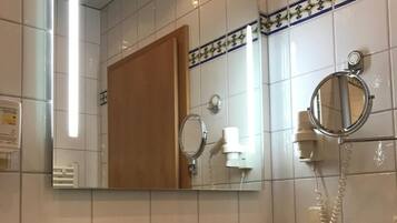 A bathroom with a sink, mirror, towel rack, and toiletries.