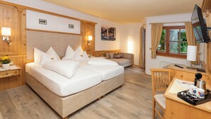 Une chambre d’hôtel avec un grand lit, un bureau avec une chaise, une télévision et une fenêtre avec des rideaux.
