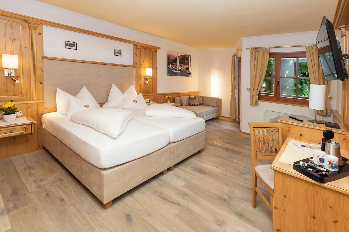 Une chambre d’hôtel avec un grand lit, un bureau avec une chaise, une télévision et une fenêtre avec des rideaux.