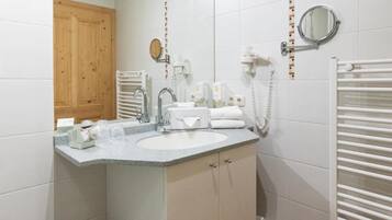 Een badkamer met een wastafel, spiegel, handdoekrek en een houten deur.