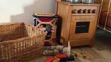A wooden cabinet with kitchenware, a wicker basket, and a toy train on a wooden floor.