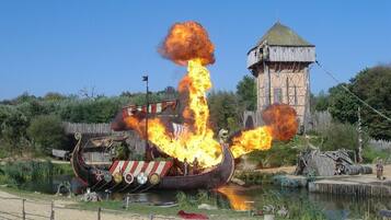 A Viking ship on fire with spectators in the foreground.