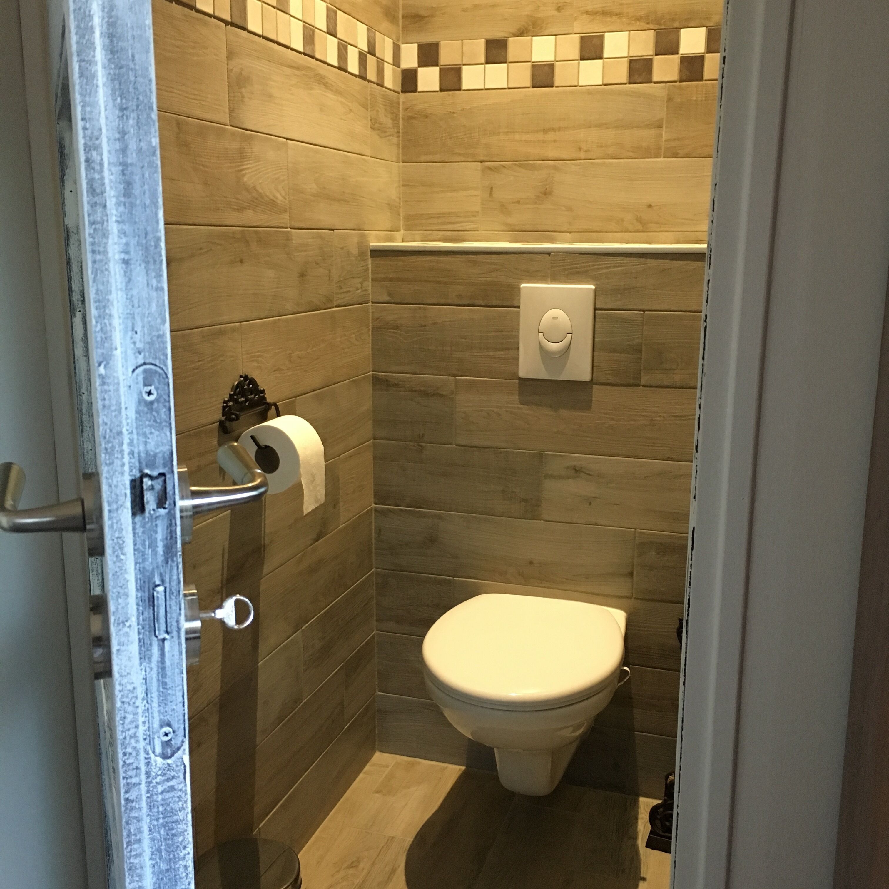A small, modern bathroom with a toilet, a hand dryer, and a paper towel dispenser.